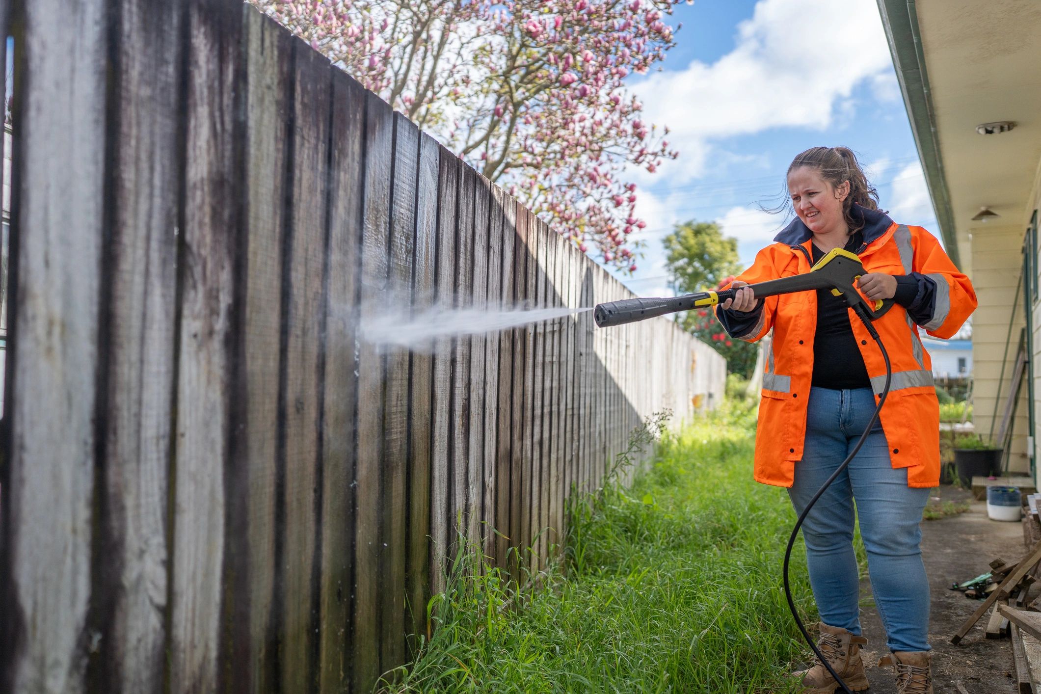 Person pressure washing a wooden fence